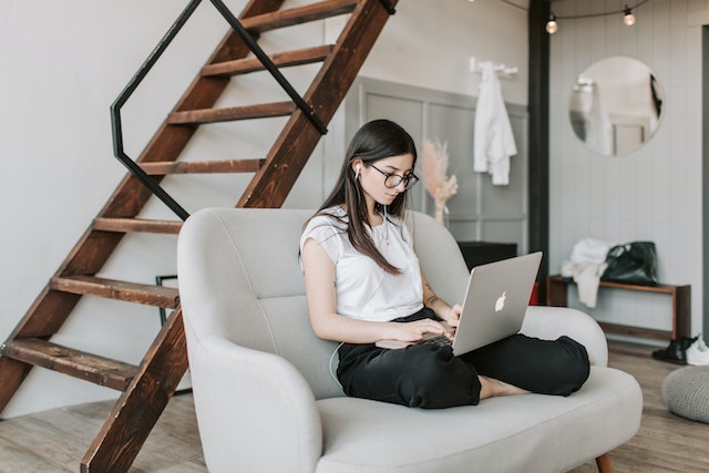 belajar bahasa inggris: Focused woman using earphones and laptop at home during work