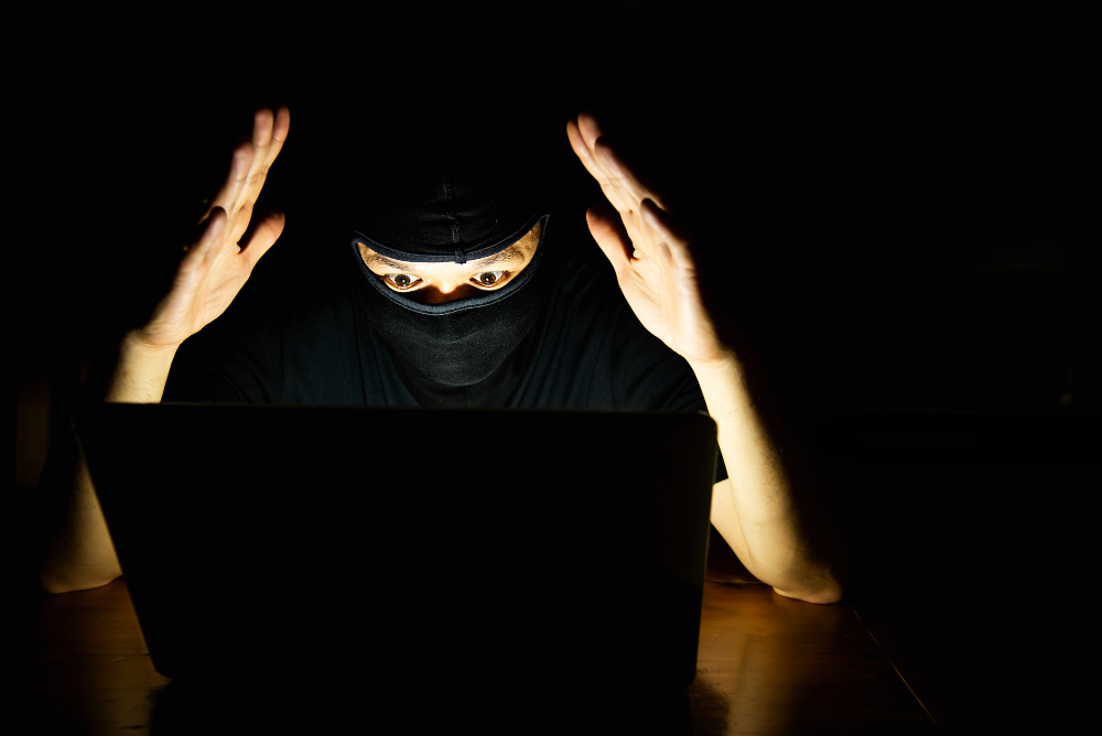 computer hacker doing his job with laptop computer dark room
