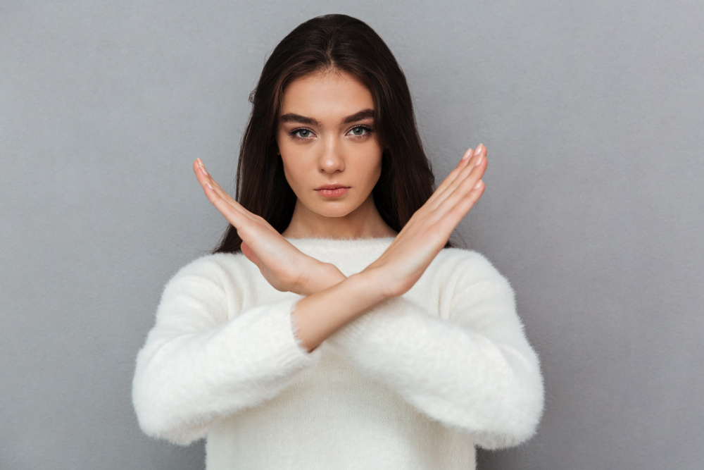 portrait serious young woman showing crossed hands gesture