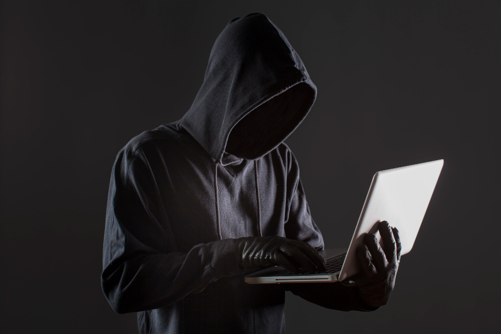 Dark web: side view male hacker with gloves laptop