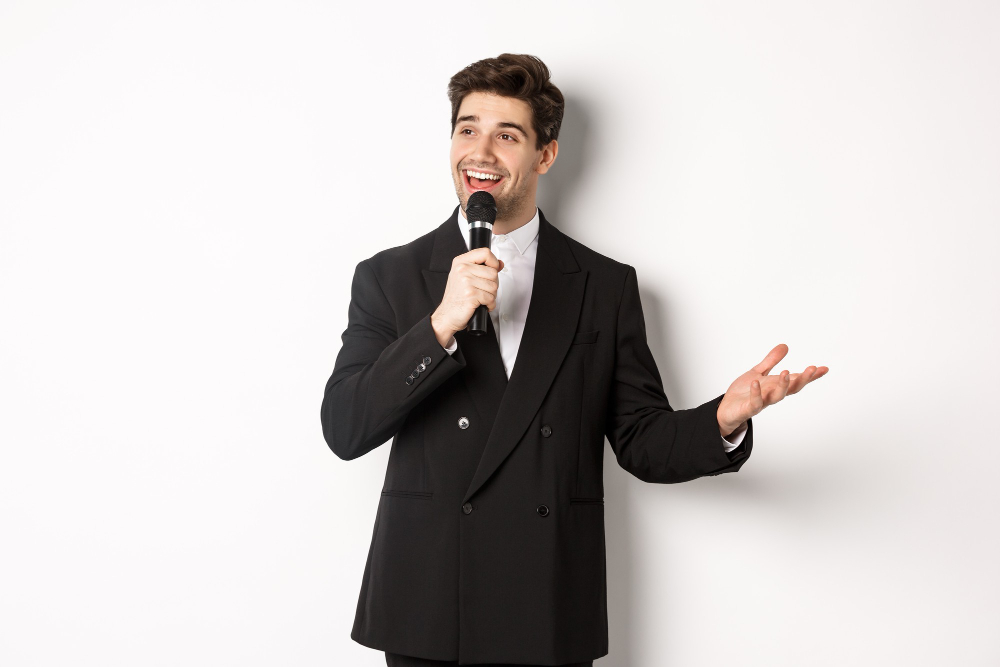 portrait handsome man black suit singing song holding microphone giving speech standing against white background