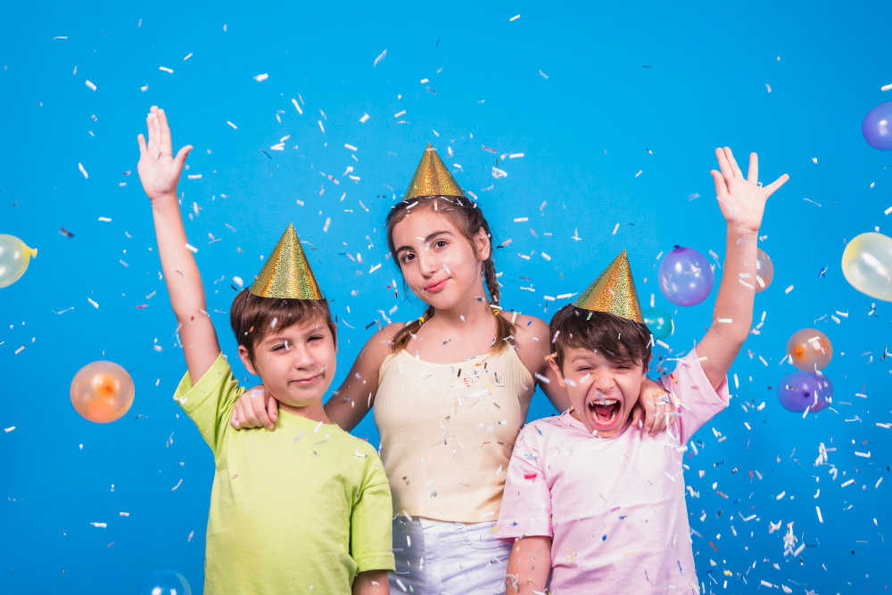 close up cheerful siblings with confetti balloons blue backdrop