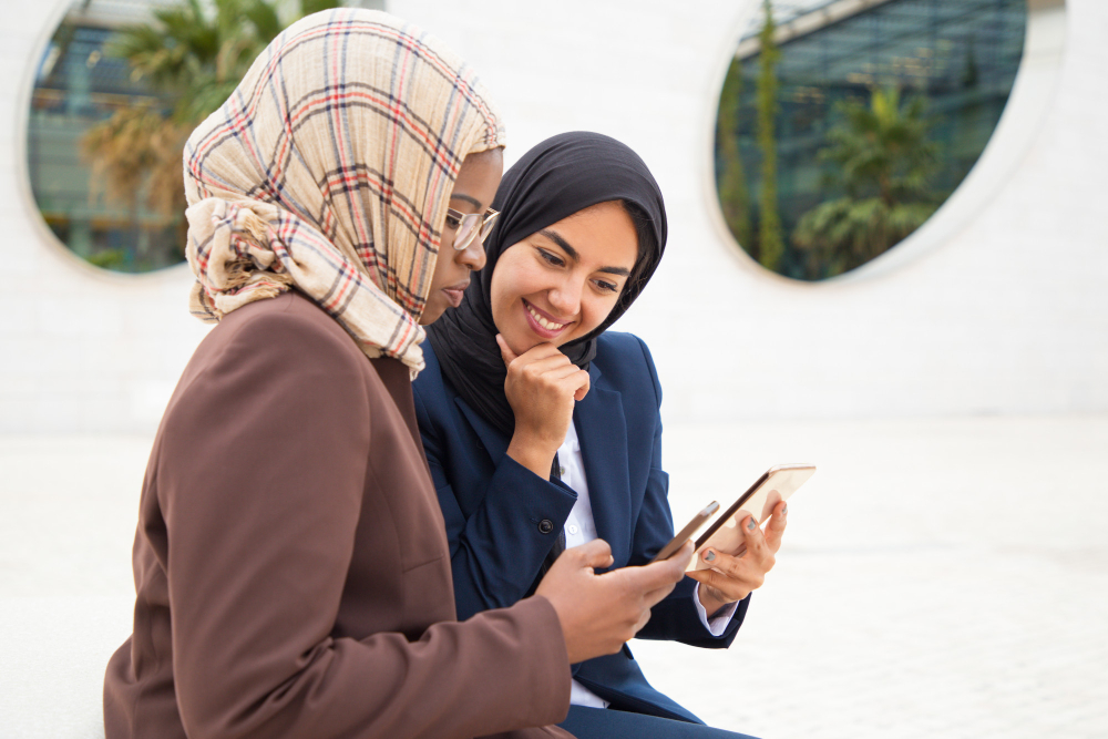 Contoh Bank Syariah: Rekan kantor yang bersemangat menggunakan ponsel