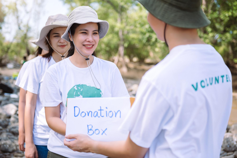 Apa itu relawan: Sekelompok sukarelawan dari berbagai negara di Asia memegang kotak sumbangan untuk penggalangan dana dalam situasi darurat seperti membantu korban banjir di Ukraina, acara amal makanan untuk anak-anak.